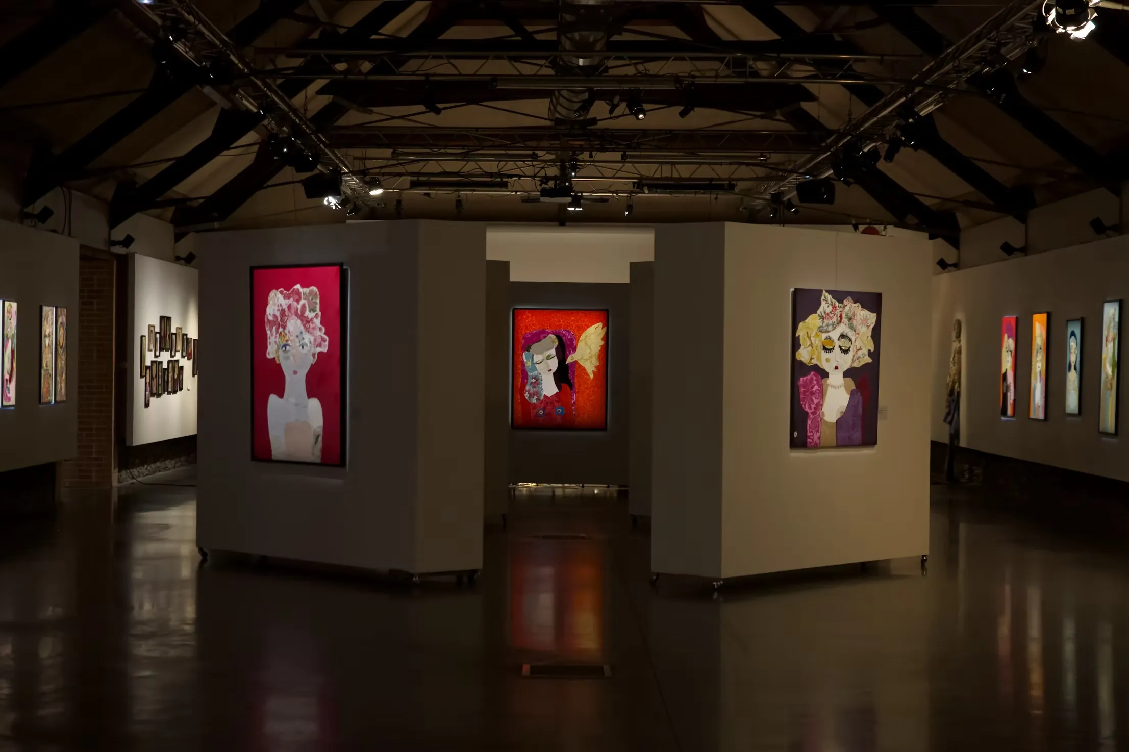 Salle d'exposition aux Anciennes Écuries de Trélazé, portraits textiles de Katherine Roumanoff accrochés sur cloisons blanches, charpente apparente