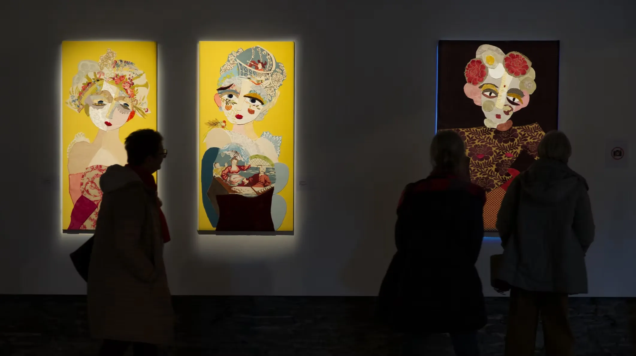 Deux grands portraits textiles féminins sur fond jaune, série Vénus de Katherine Roumanoff, visiteurs en silhouette, exposition Trélazé Angers