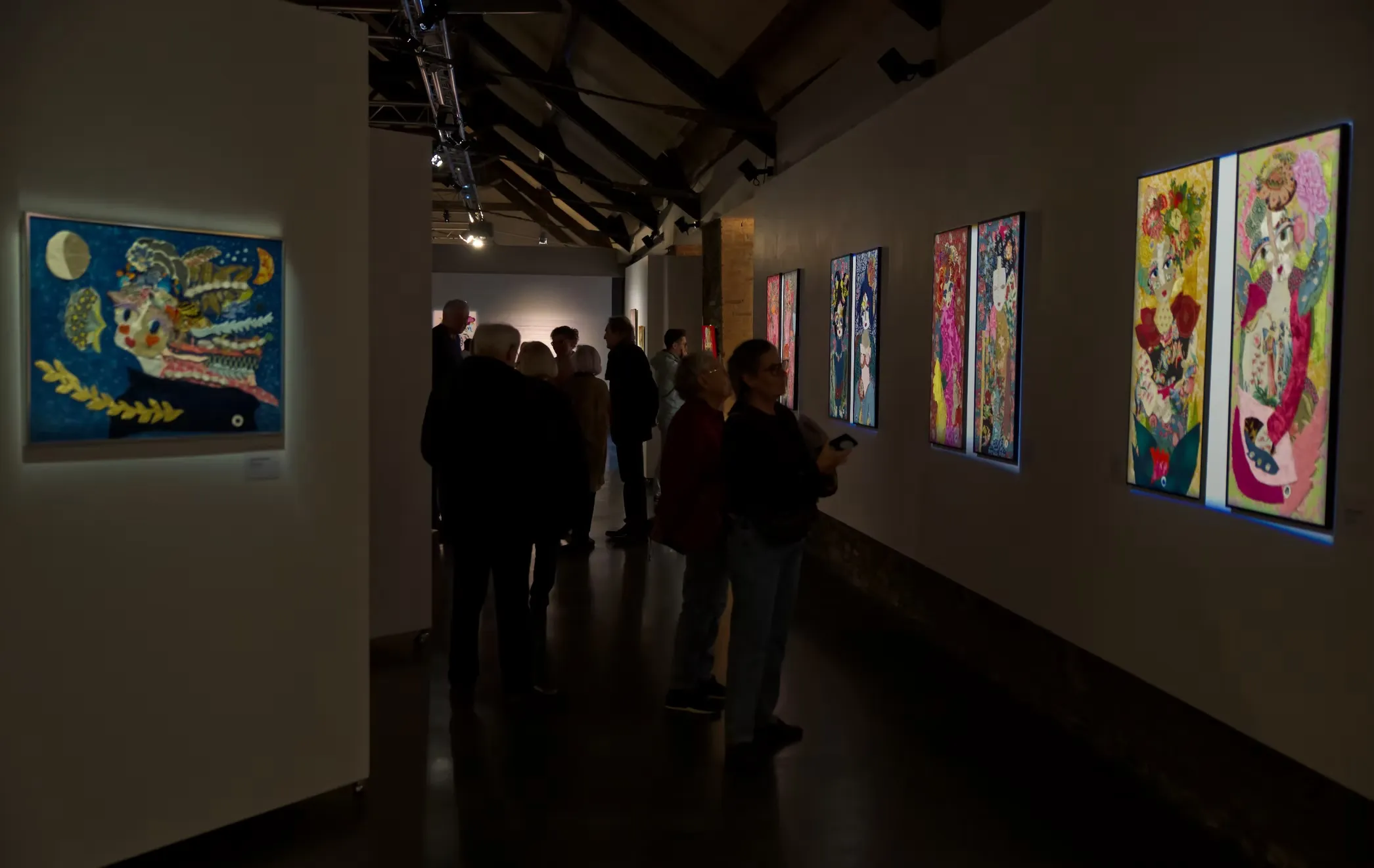 Grande salle d'exposition avec foule de visiteurs, œuvres textiles de Katherine Roumanoff accrochées aux murs, Anciennes Écuries de Trélazé Angers