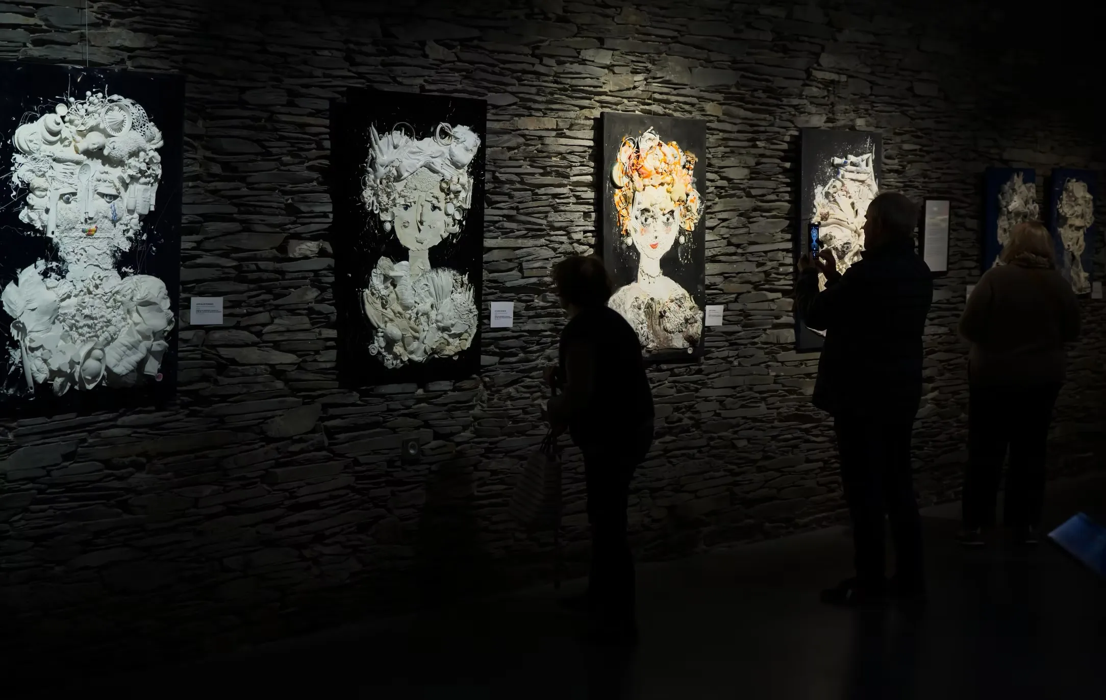 Sculptures blanches de formes humaines sur fond de mur sombre, série Toiles-sculptures de Katherine Roumanoff, exposition Trélazé Angers